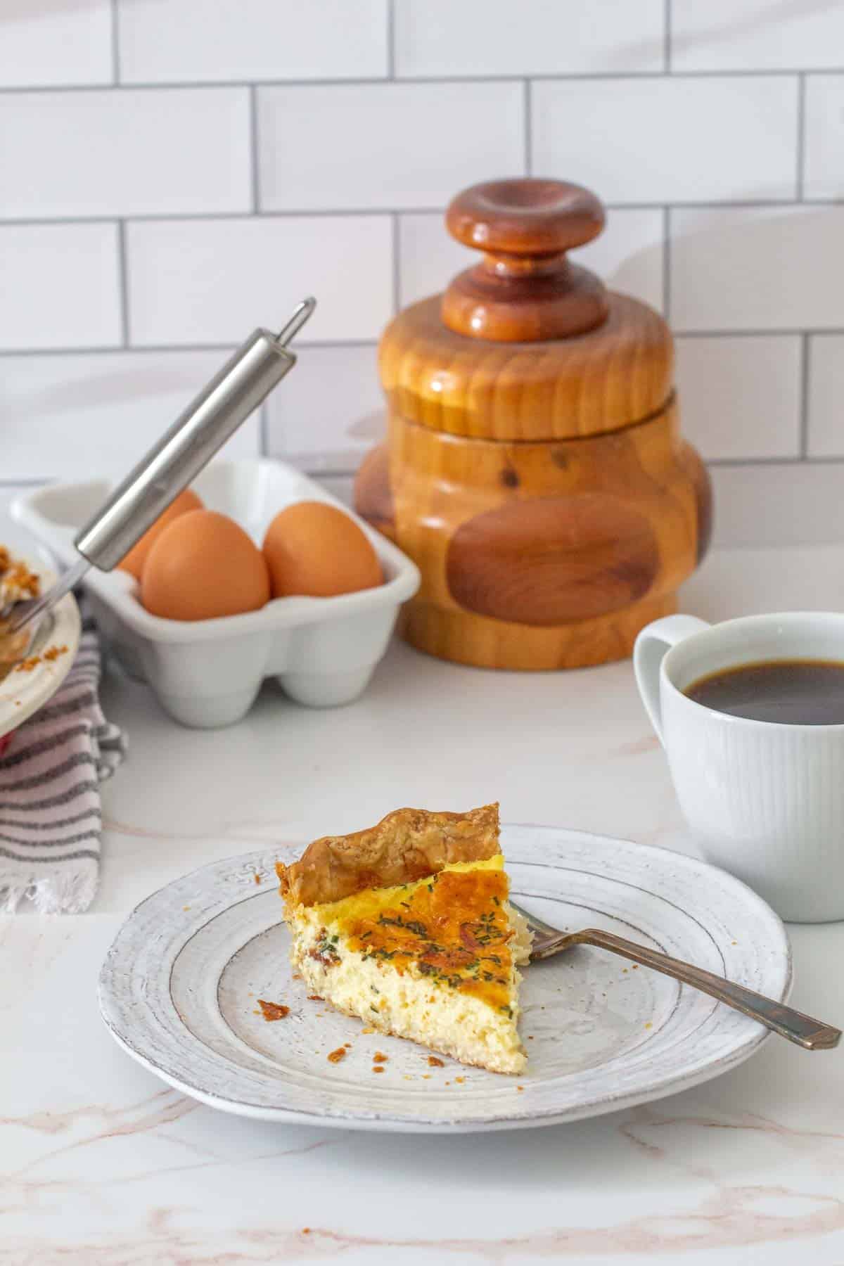 slice of cheese quiche with fork and coffee beside