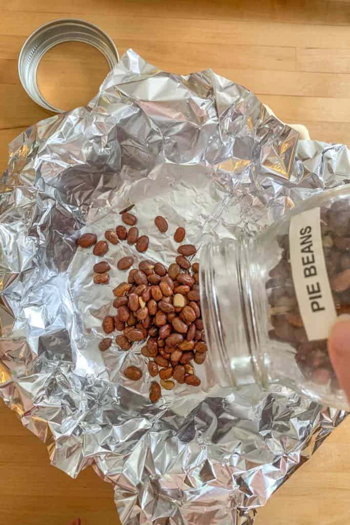 pouring pie beans into crust for blind baking