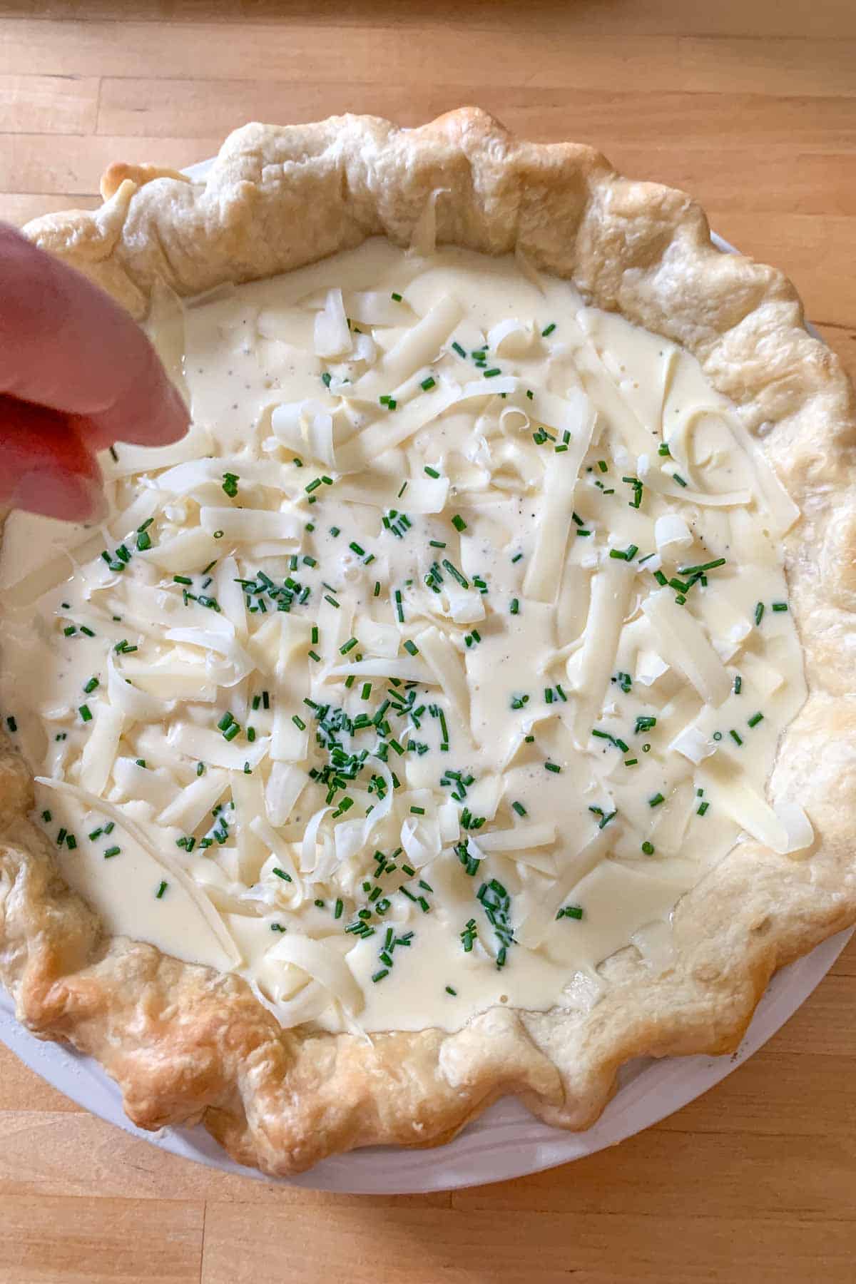 adding chives to unbaked cheese quiche