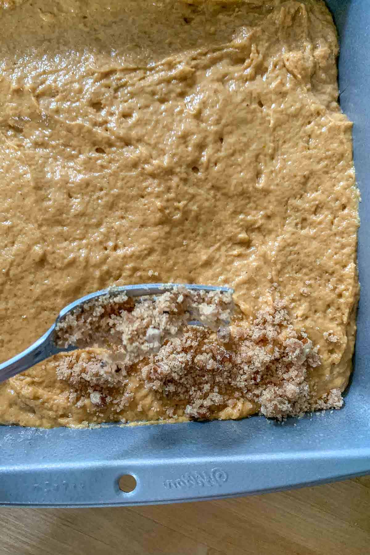 adding streusel topping to pumpkin coffee cake