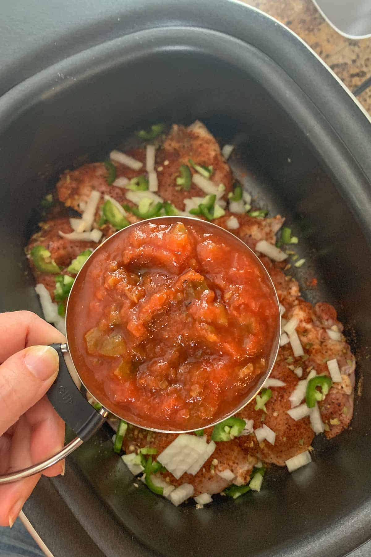 adding salsa to slow cooker chicken tacos