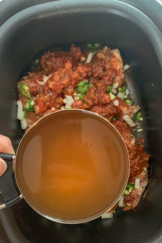 adding broth to slow cooker chicken tacos