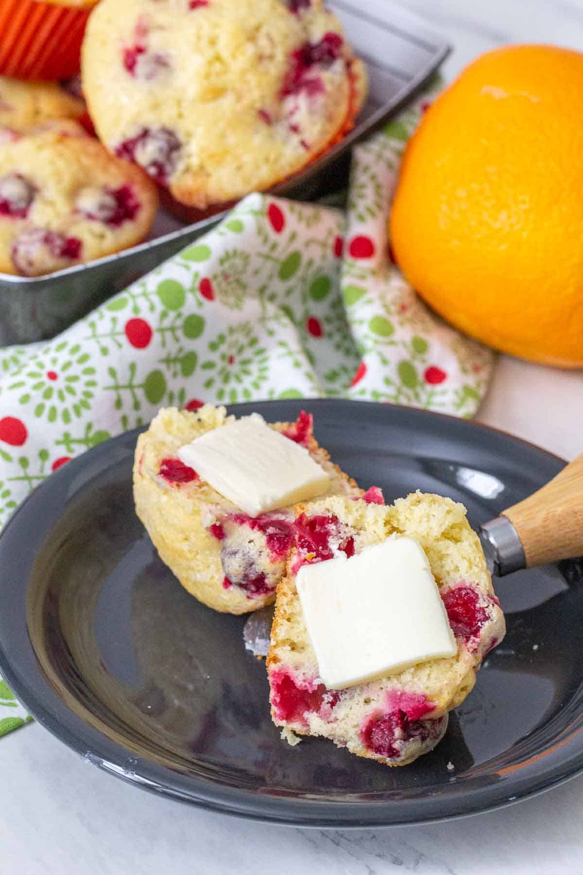 halved cranberry orange muffin with butter on a plate