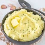 black bowl of garlic mashed potatoes with butter