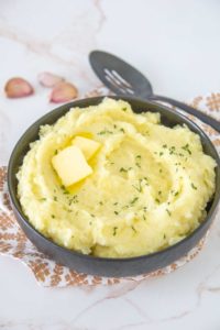 black bowl of garlic mashed potatoes with butter