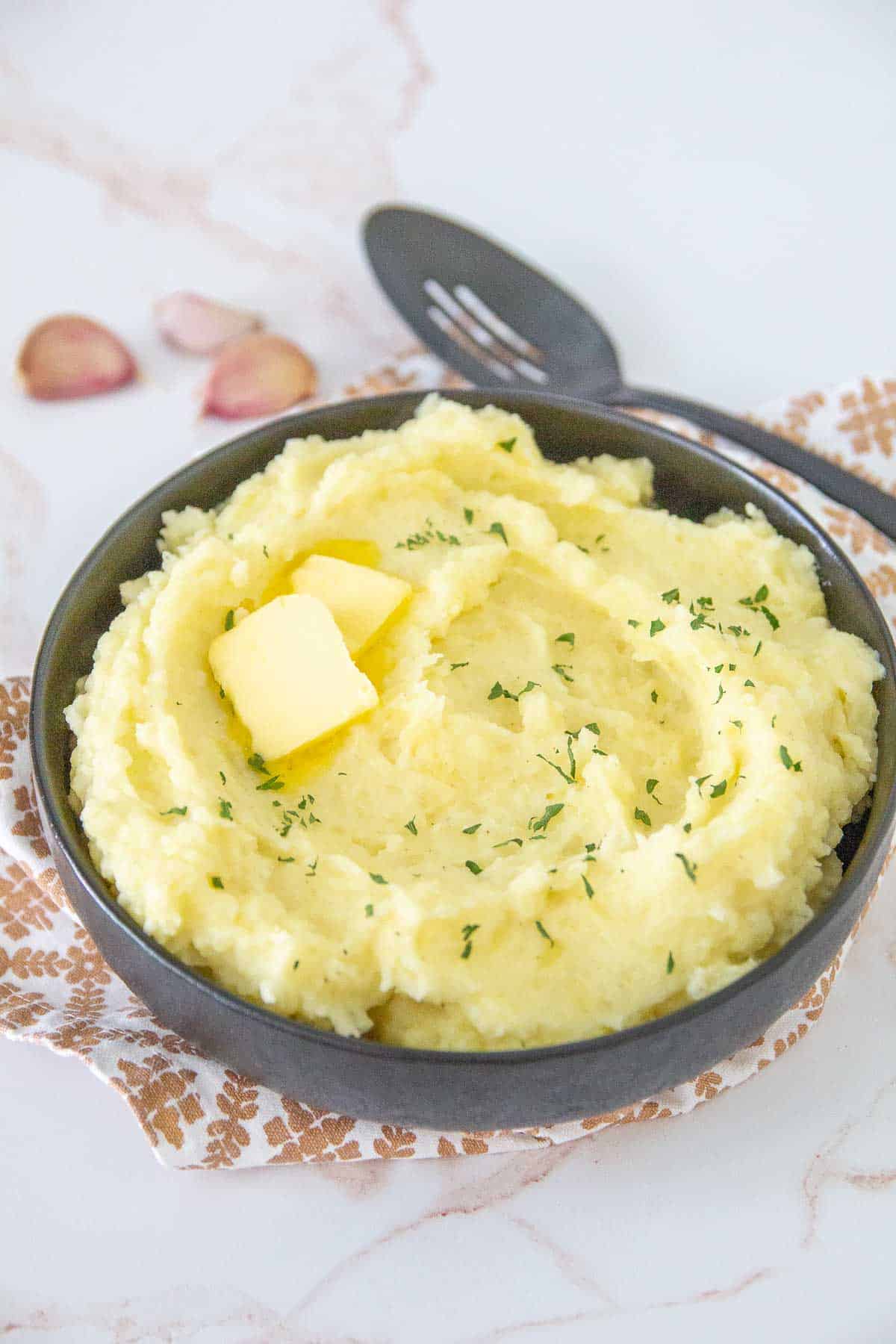 black bowl of garlic mashed potatoes with butter
