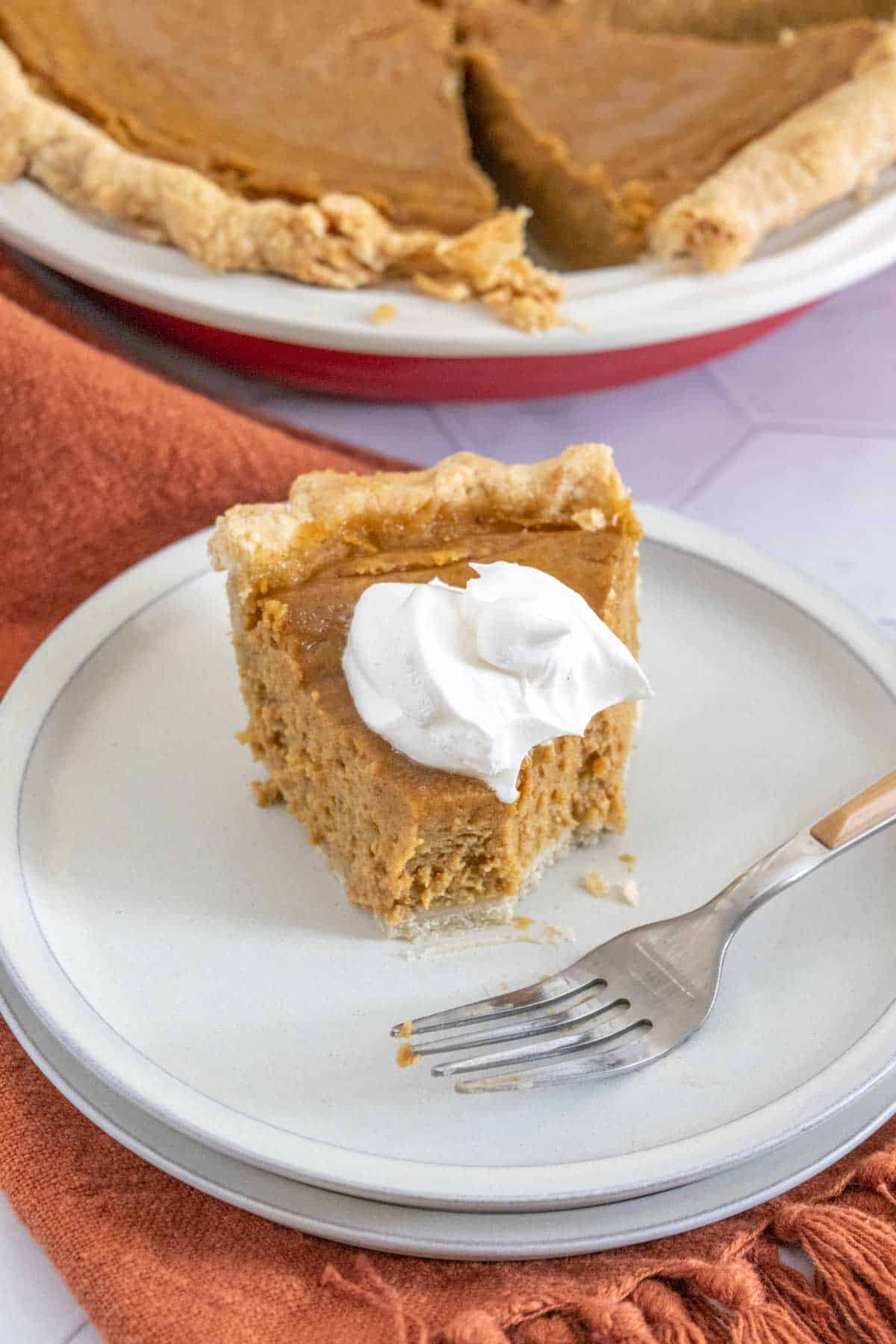 slice of butternut squash pie with whipped cream, half eaten