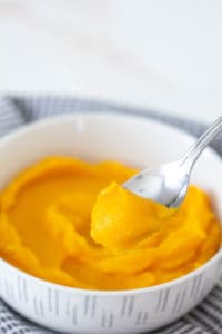 bowl of butternut squash puree with a spoon scooping some out