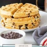 A stack of golden chocolate chip waffles is on a white plate, with a small bowl of chocolate chips and a brown pitcher nearby. Text reads "Delicious chocolate chip waffles.