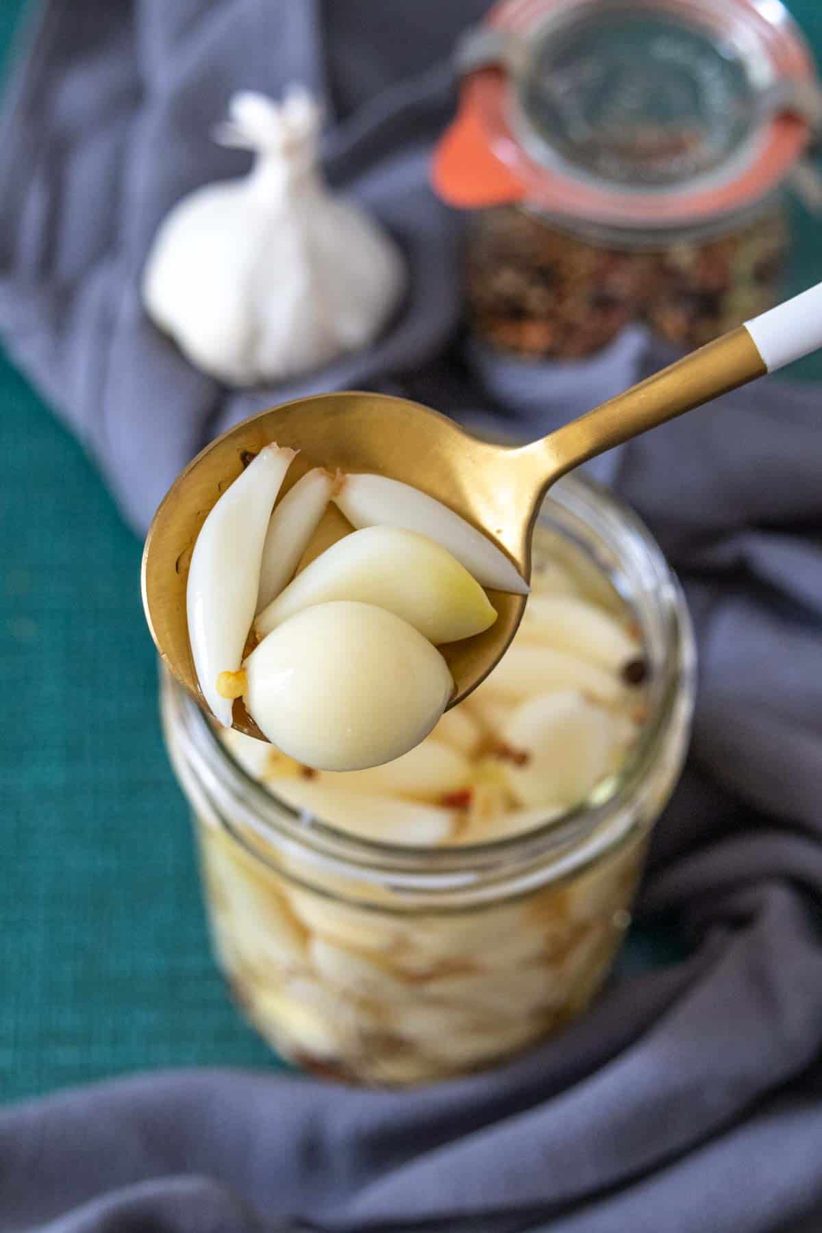 pickled garlic cloves on a gold spoon with white handle