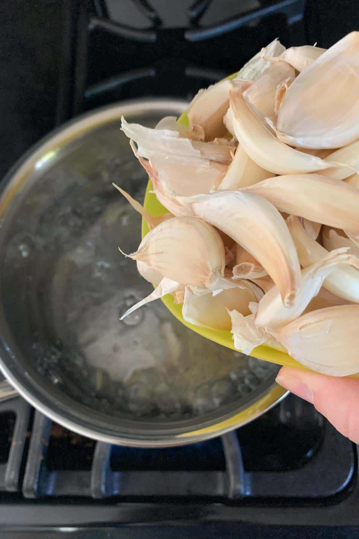 adding garlic cloves to boiling water