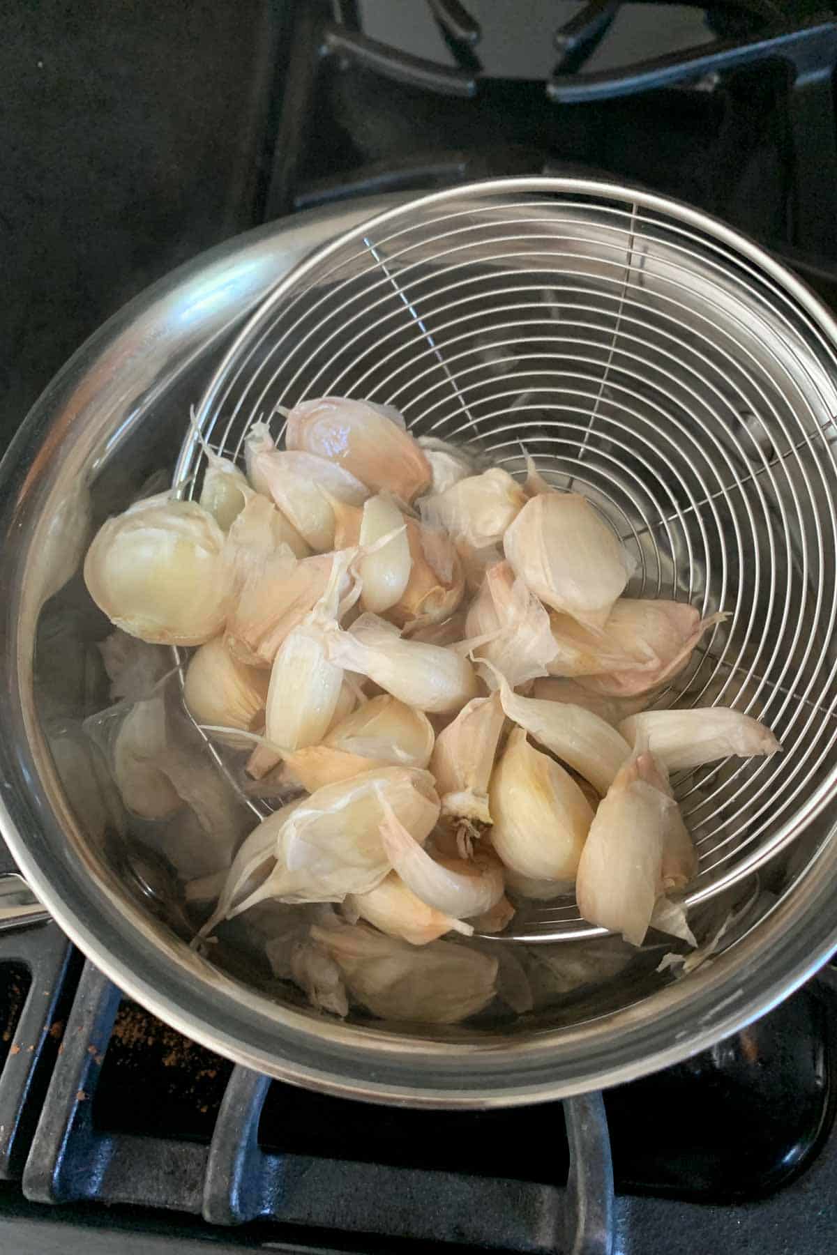 straining garlic from boiling water
