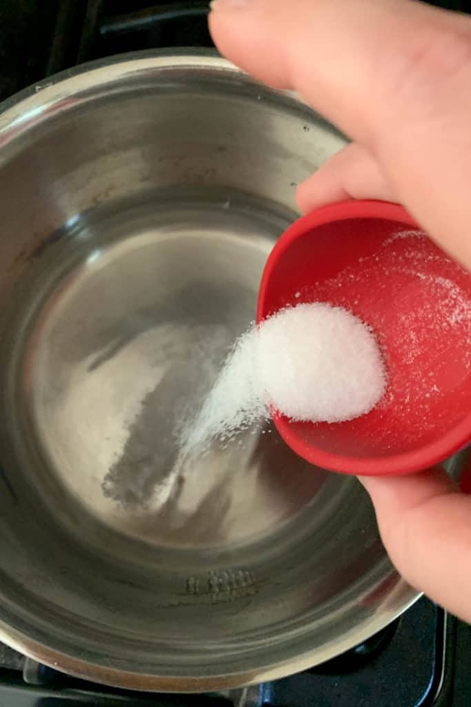 adding salt and sugar to vinegar for pickle brine