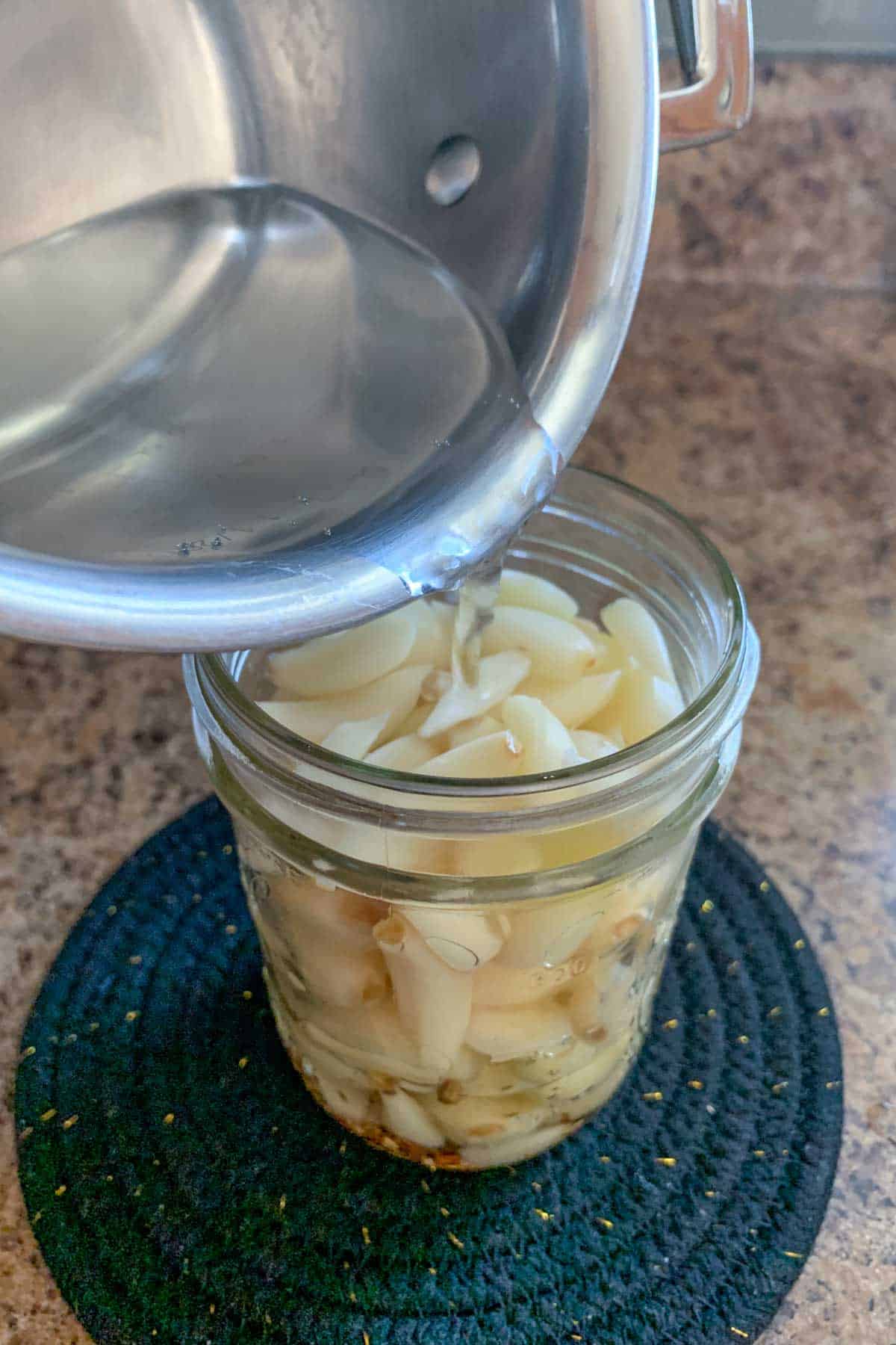 pouring brine into jar with garlic