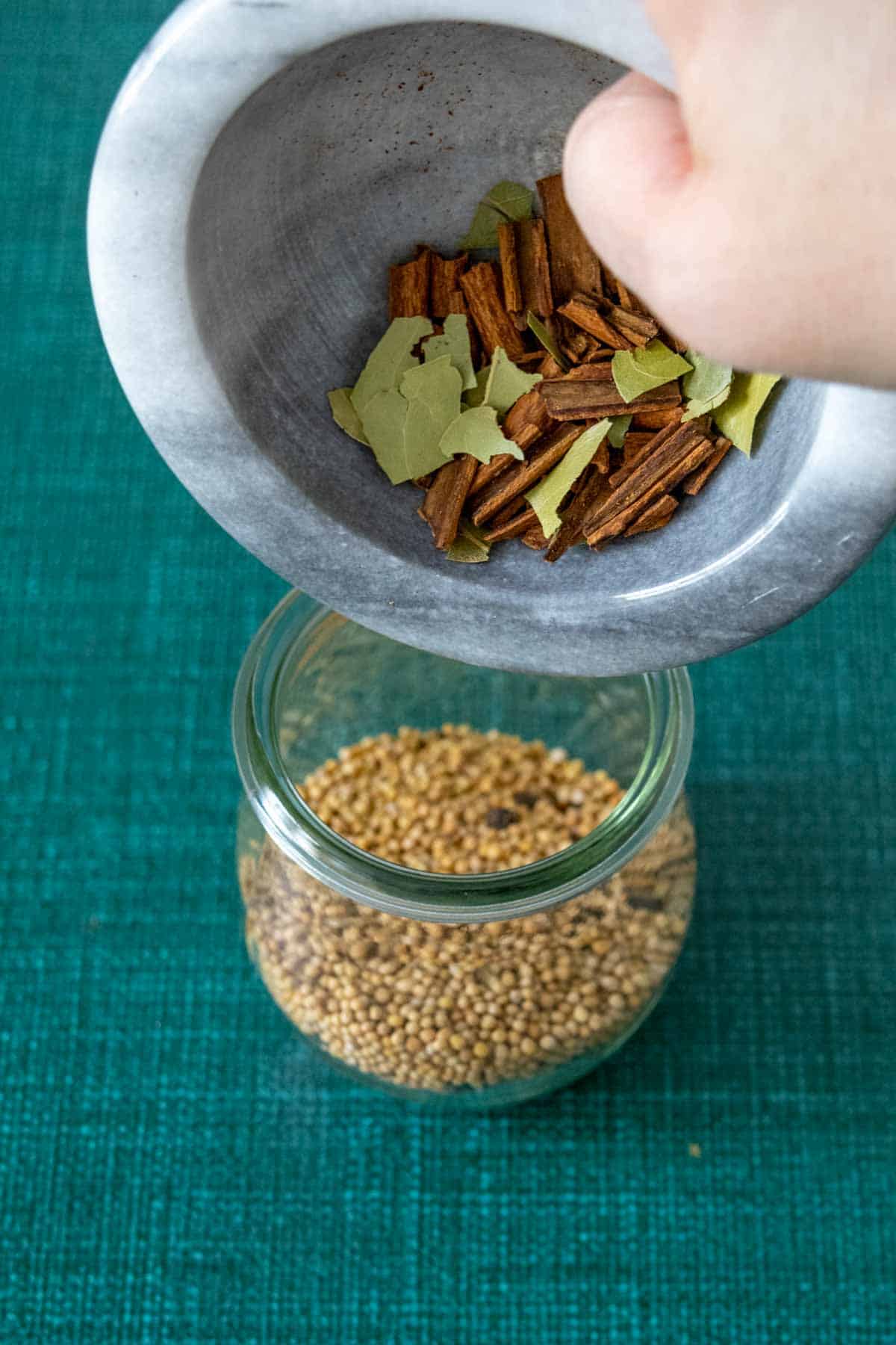 pouring crushed bay and cinnamon into jar