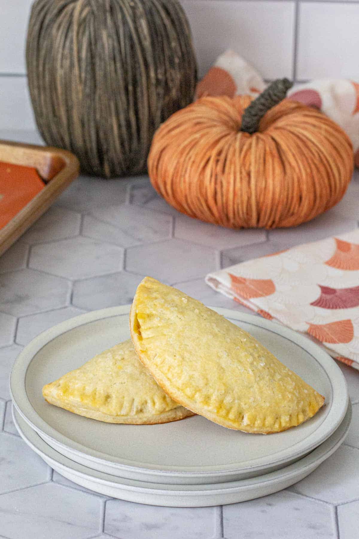 Two pumpkin empanadas on a gray plate.