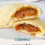A plate with pumpkin empanadas, one of which is cut open to reveal the delicious pumpkin filling inside. These pumpkin empanadas are a perfect fall treat.