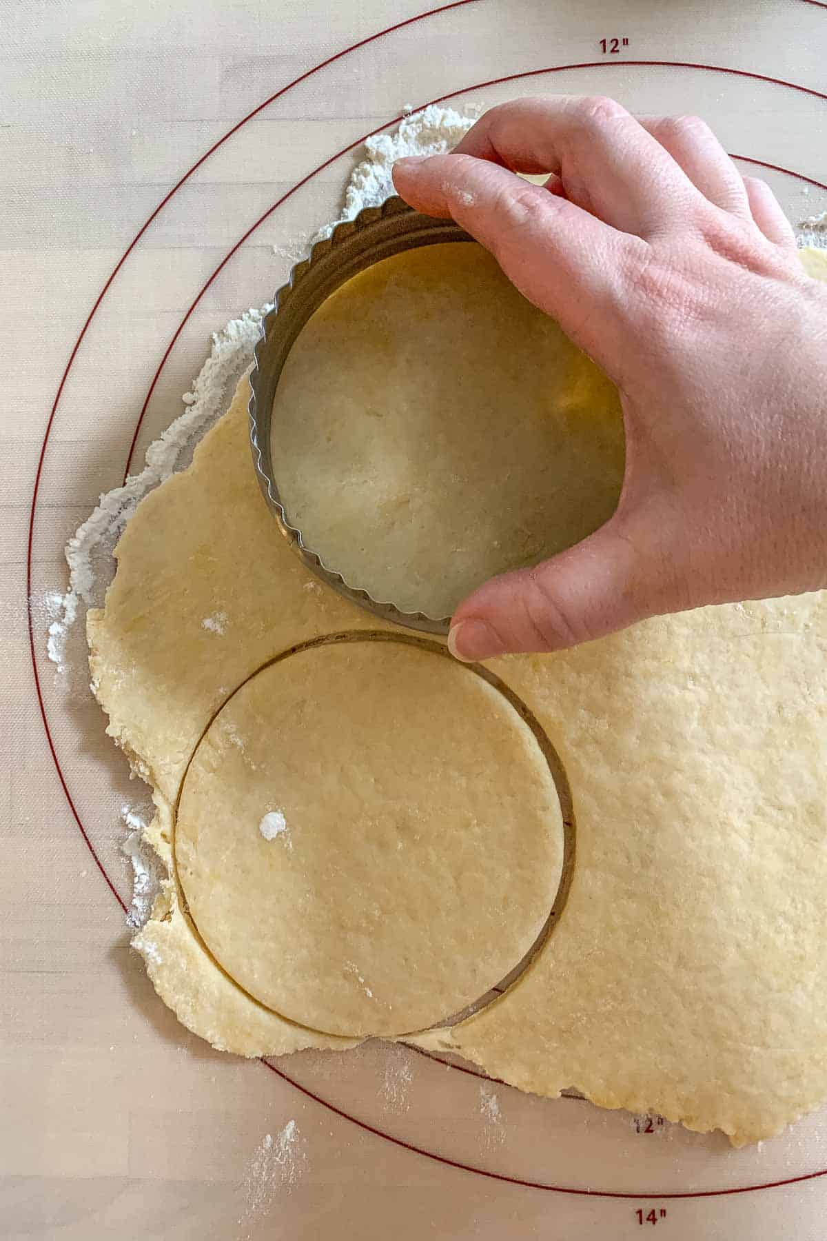 Using a round cutter to cut out empanada dough circles.