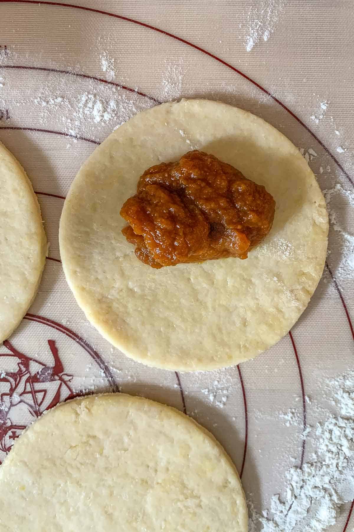 Empanada dough circles with pumpkin filling in the center.
