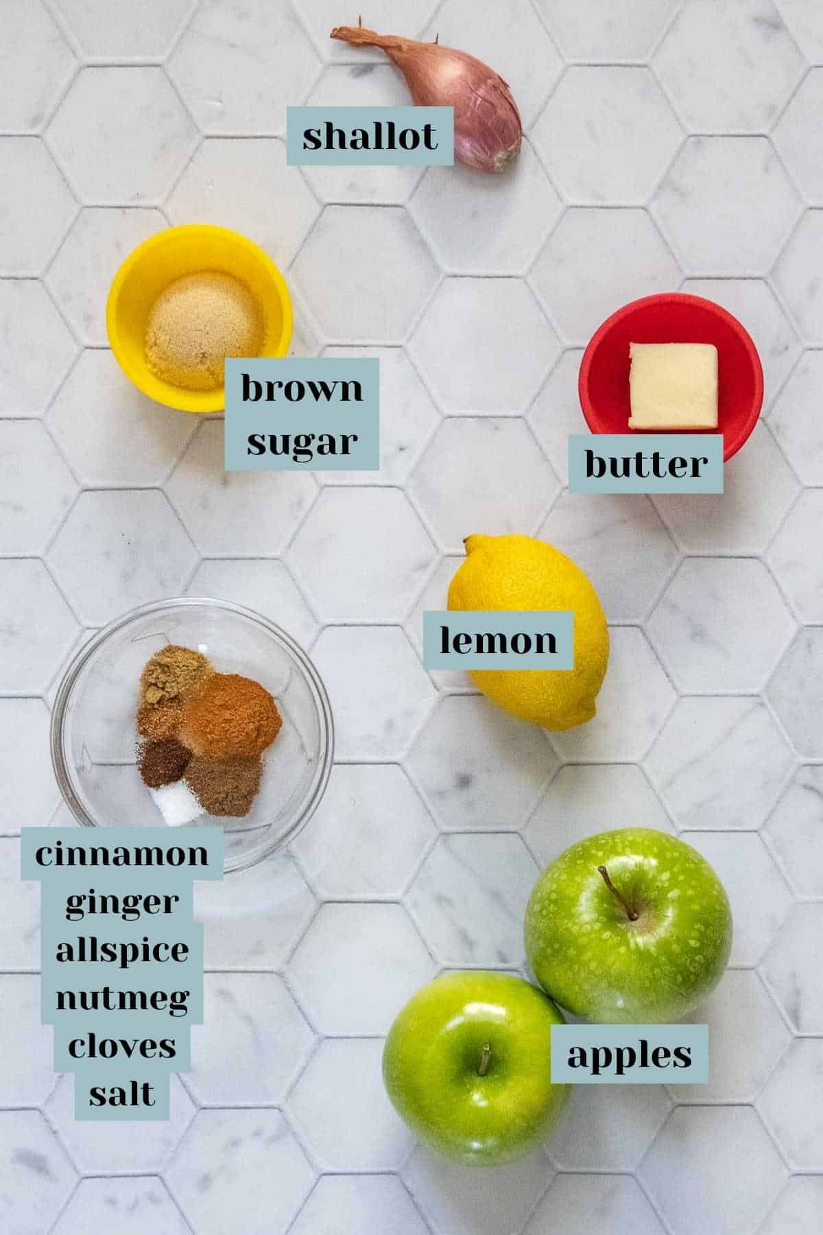 Ingredients for apple compote on a tile surface with labels.
