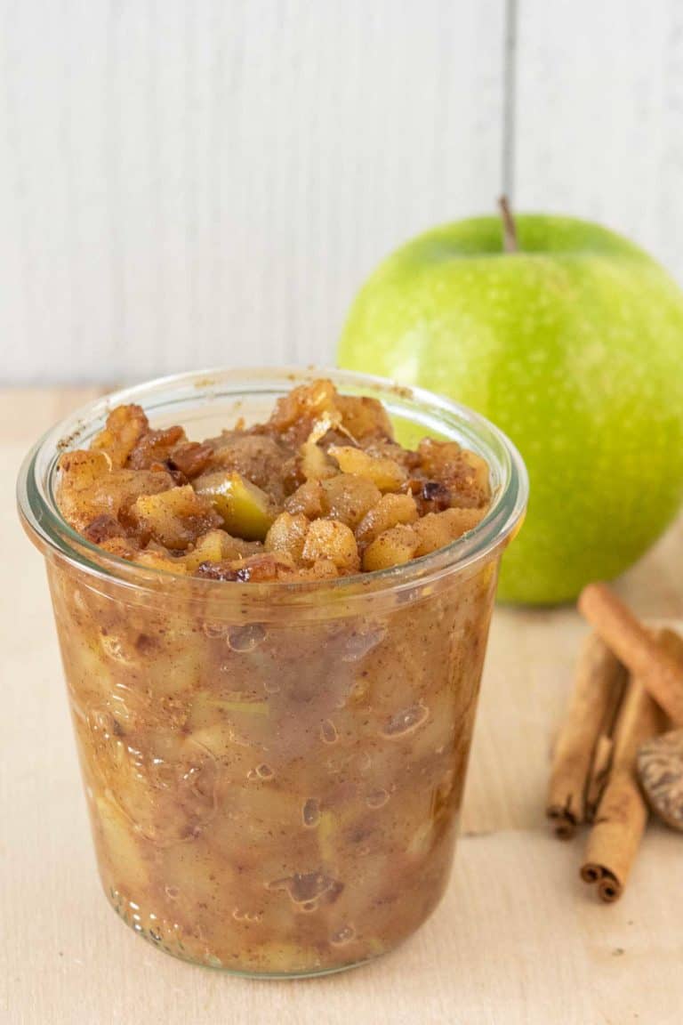 Jar of apple compote with ingredients behind.