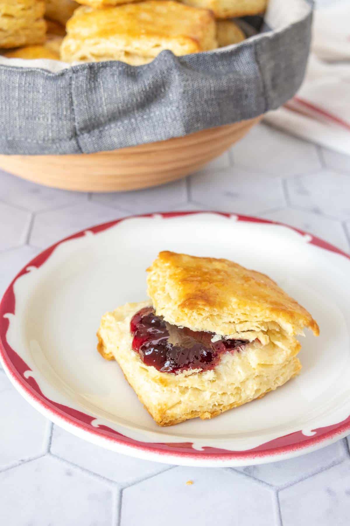 Split buttermilk biscuit on a plate with blueberry jam on top.