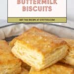 A basket of square, golden-brown buttermilk biscuits sits below a sign reading "Buttermilk Biscuits - Get the recipe at stetted.com." These fluffy buttermilk biscuits are perfect for any meal.