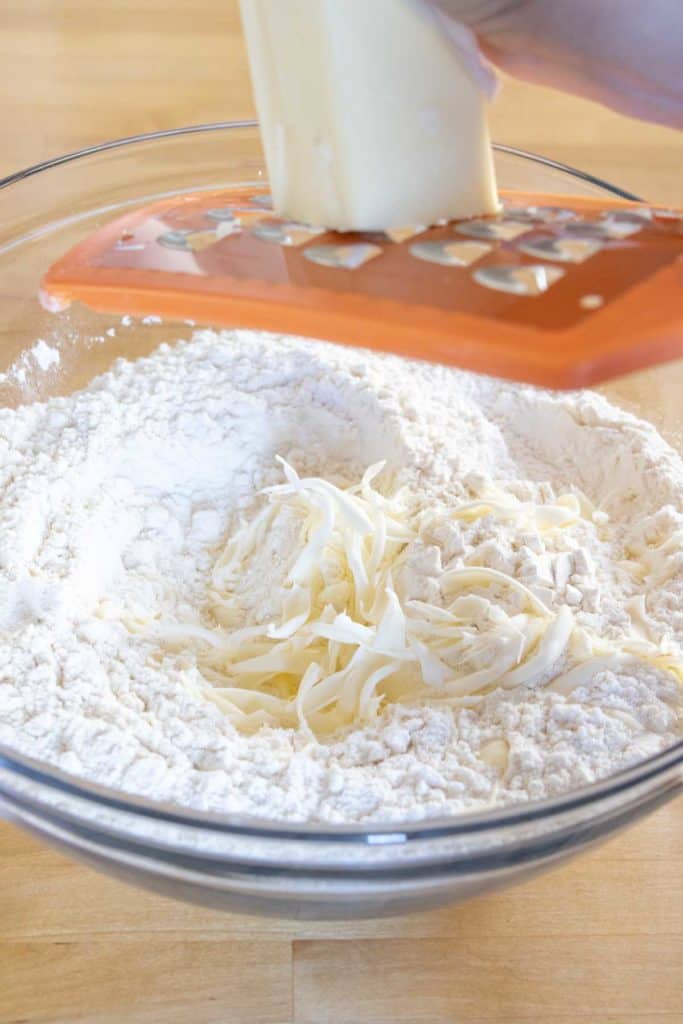 Grating frozen butter into dry ingredients for biscuits.