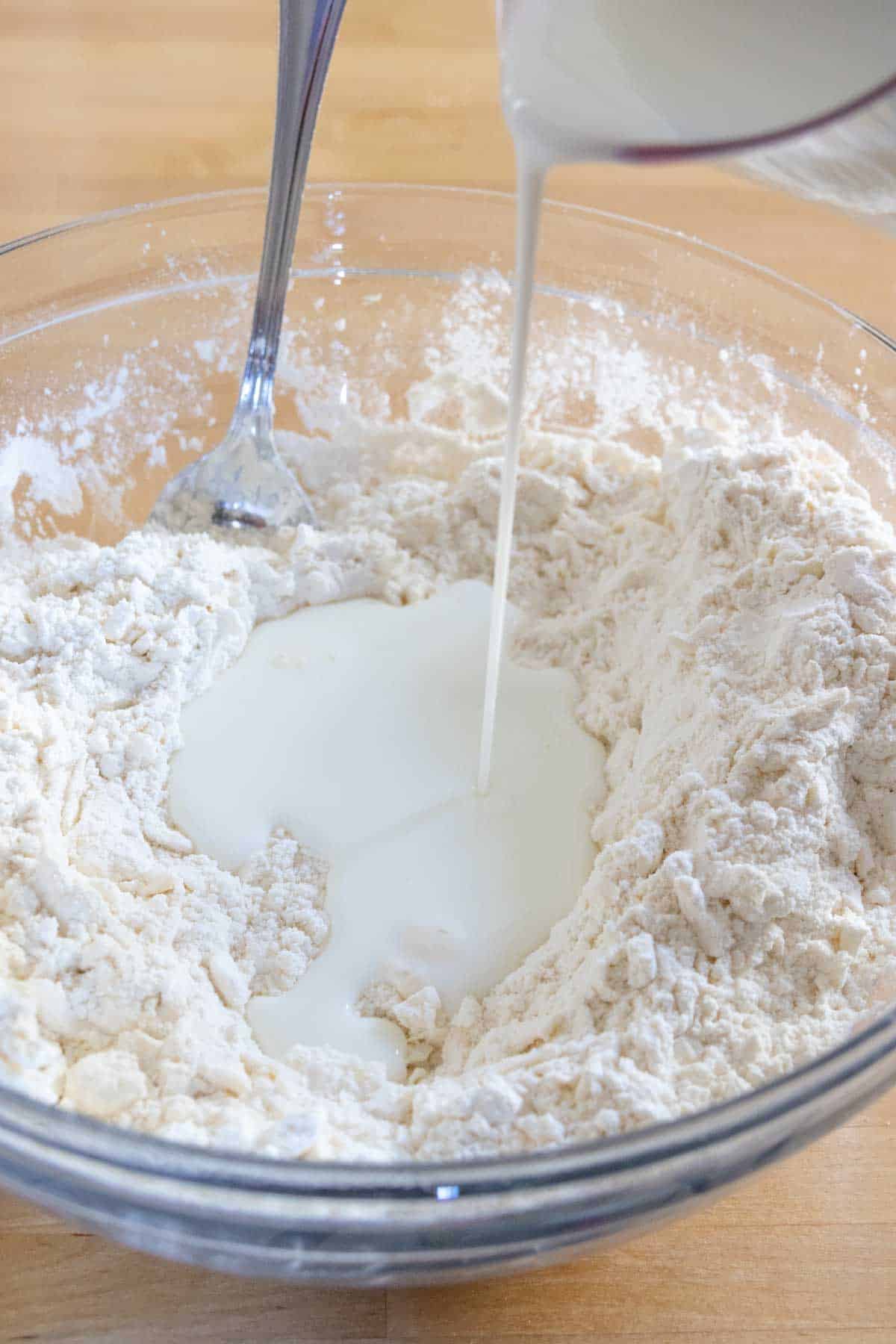 Pouring buttermilk into biscuit dough.