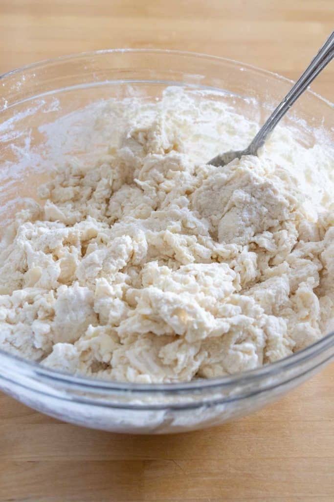 Stirring biscuit dough together in a glass bowl.