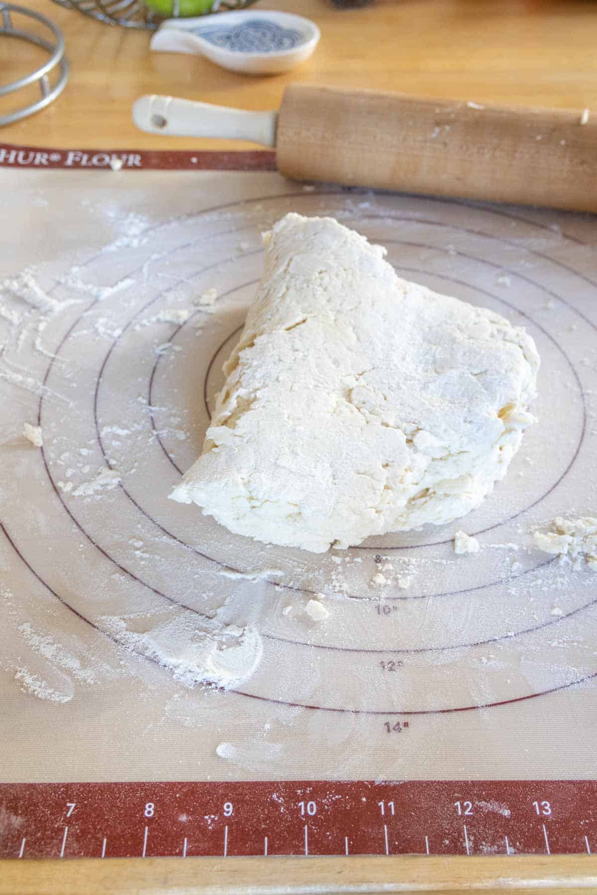 Biscuit dough folded over on a floured surface.