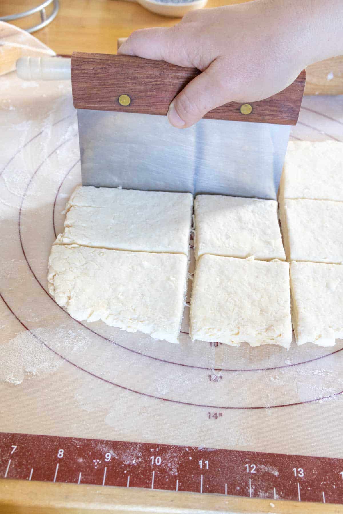 Cutting biscuit dough with a bench knife.