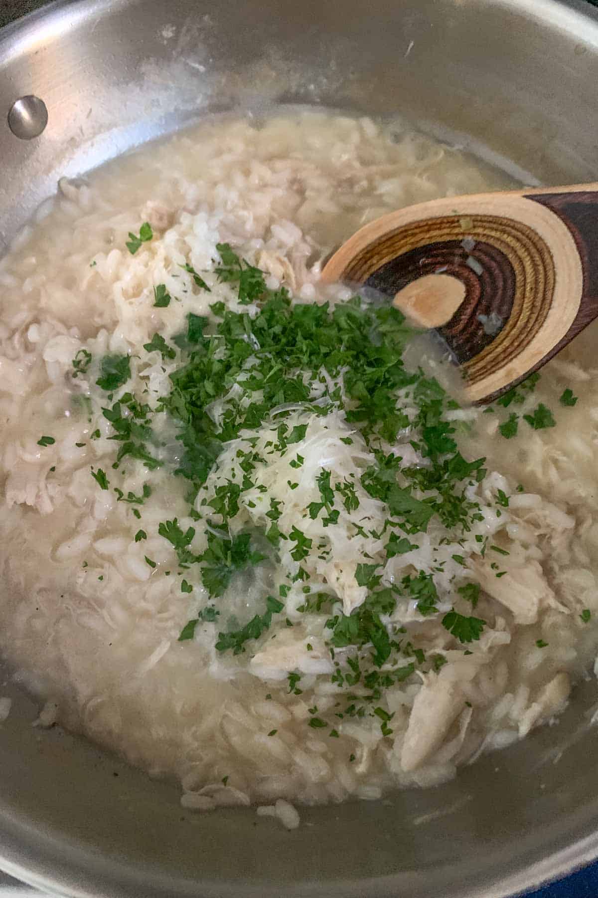 Stirring parmesan cheese and parsley into chicken risotto.
