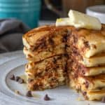 Stack of chocolate chip pancakes with a wedge cut out so the interior is seen.