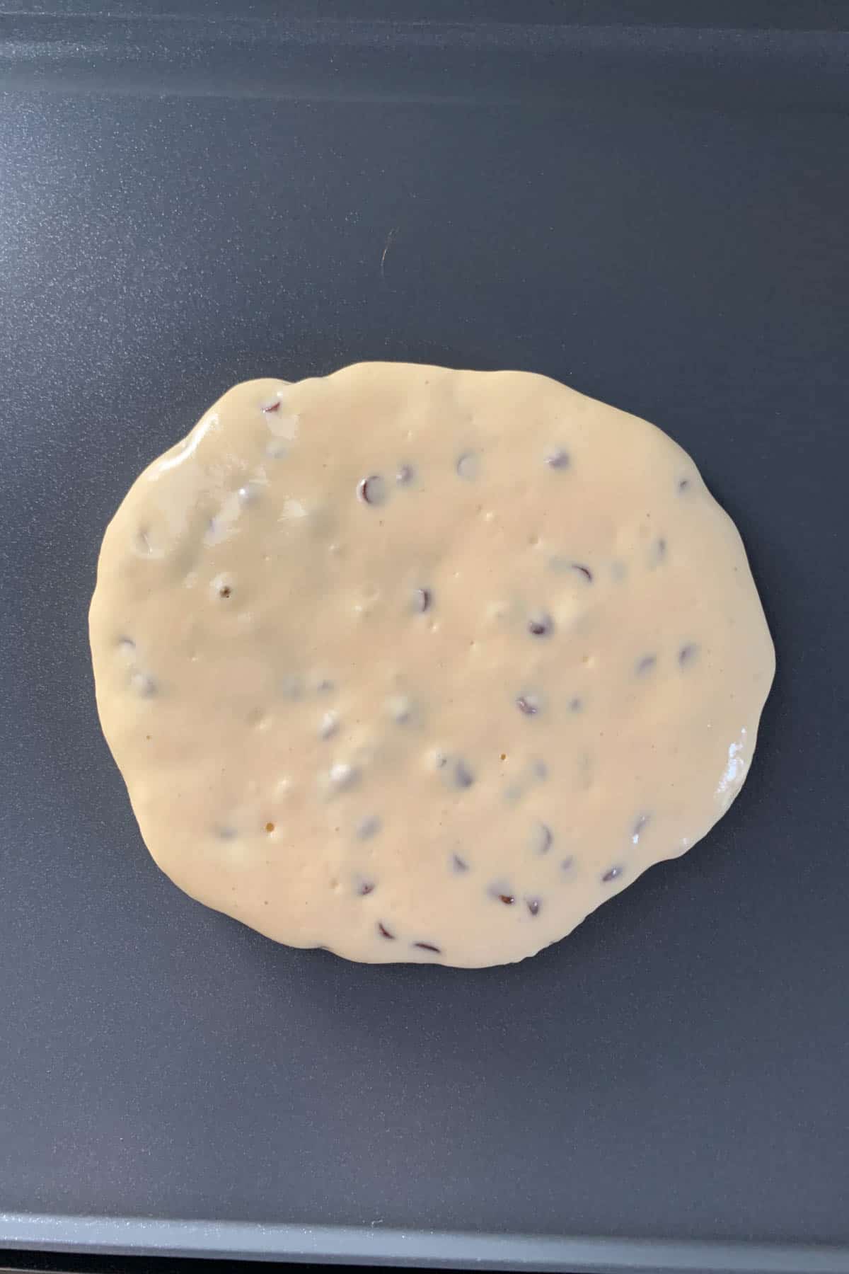 Chocolate chip pancake batter on a griddle.