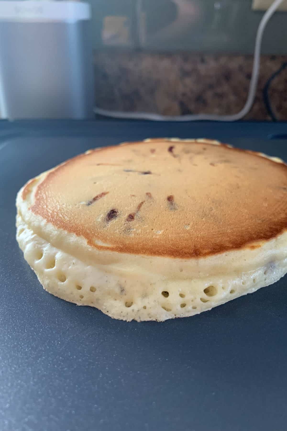 Chocolate chip pancake cooking on a griddle.