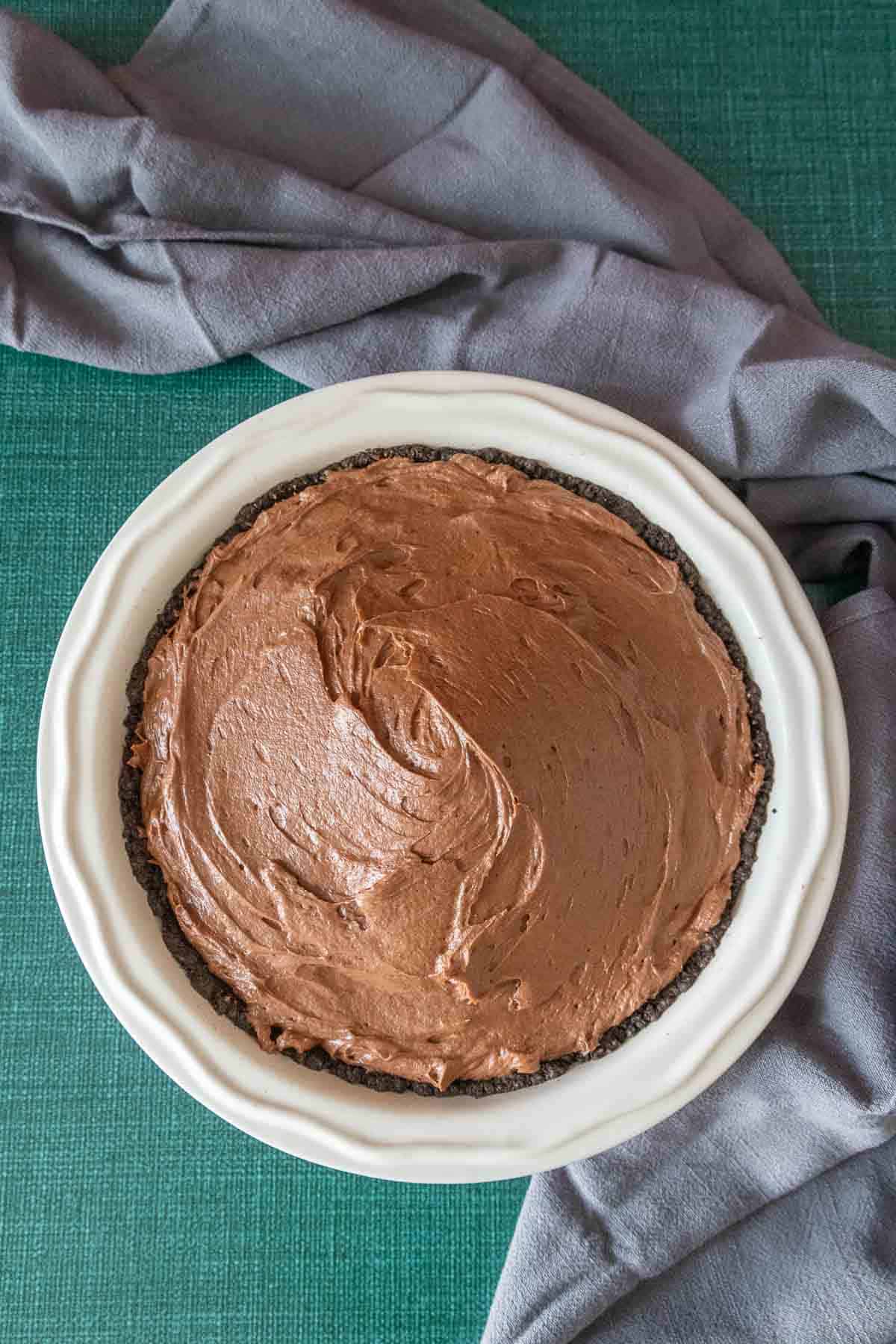 Chocolate peanut butter pie on a green surface with a gray towel.