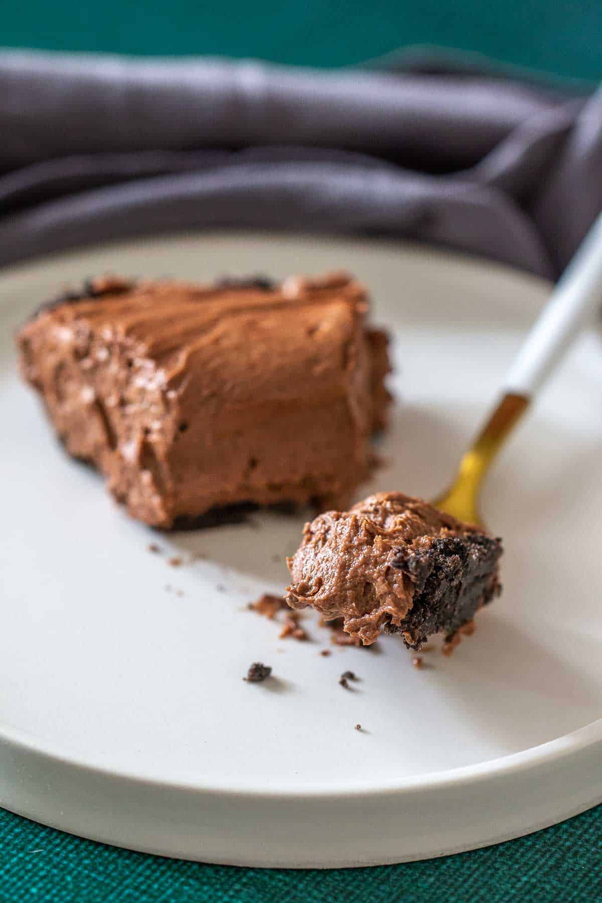 Bite of chocolate peanut butter pie on a fork resting on a white plate.