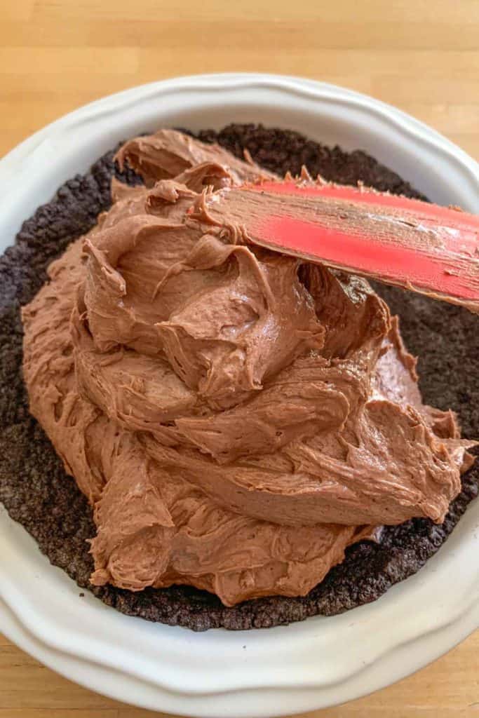 Spreading chocolate peanut butter pie filling into a crust.
