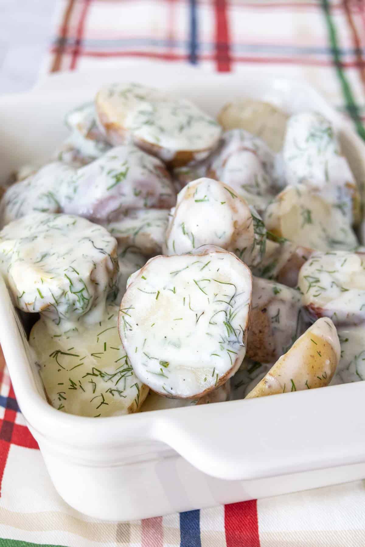 White serving dish filled with dill potatoes.
