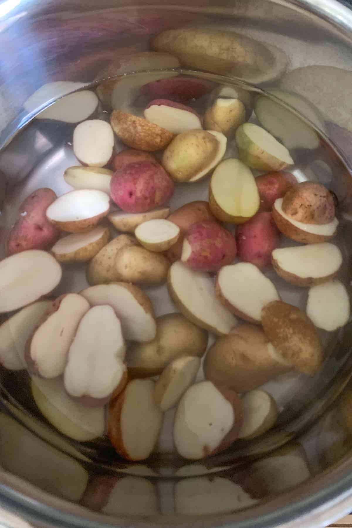Potatoes in water being set to cook in a pan.