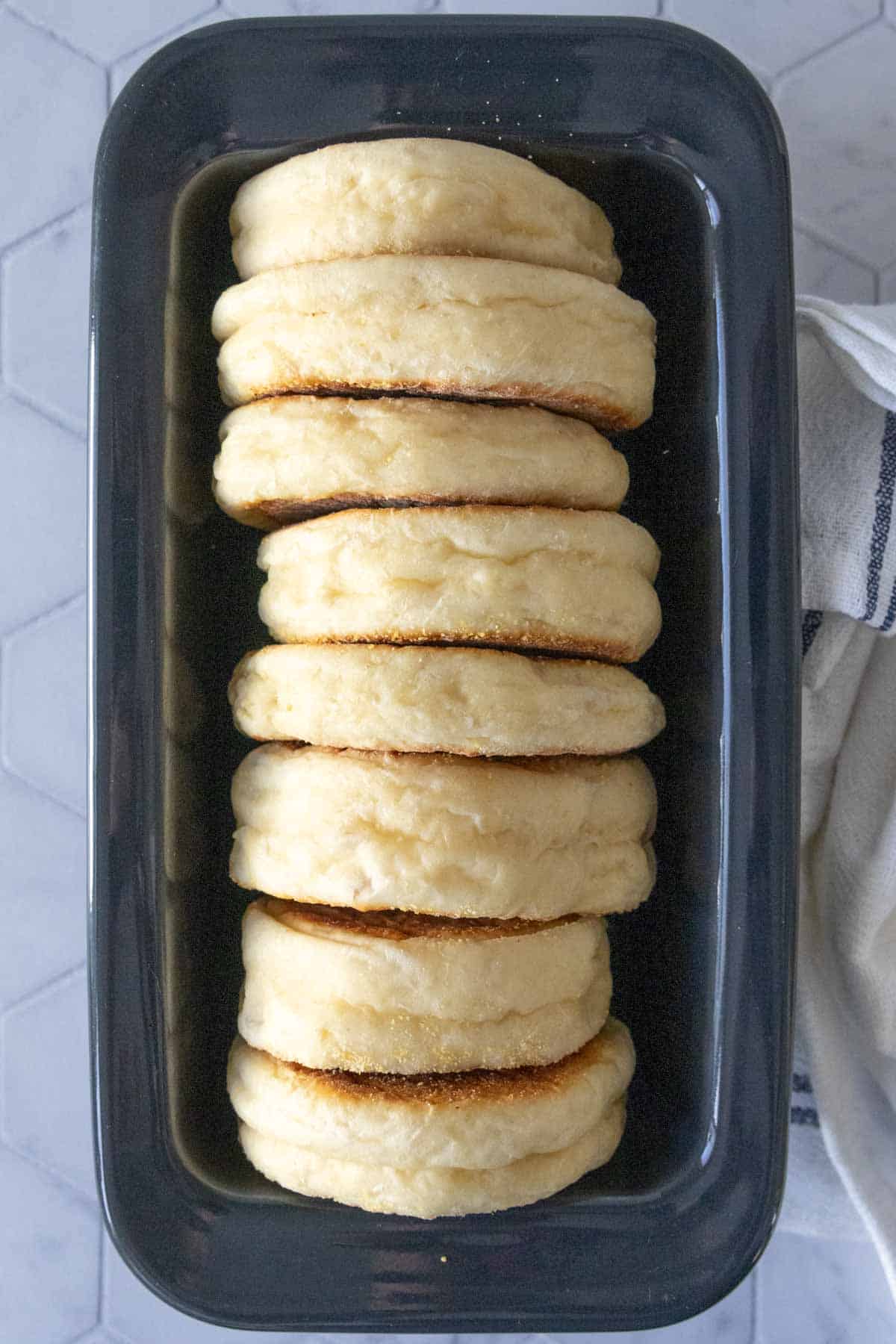 Homemade English muffins in a black ceramic loaf pan.