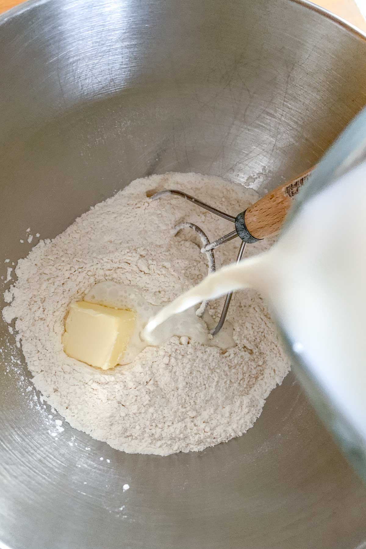 Pouring milk into dry ingredients for dough.
