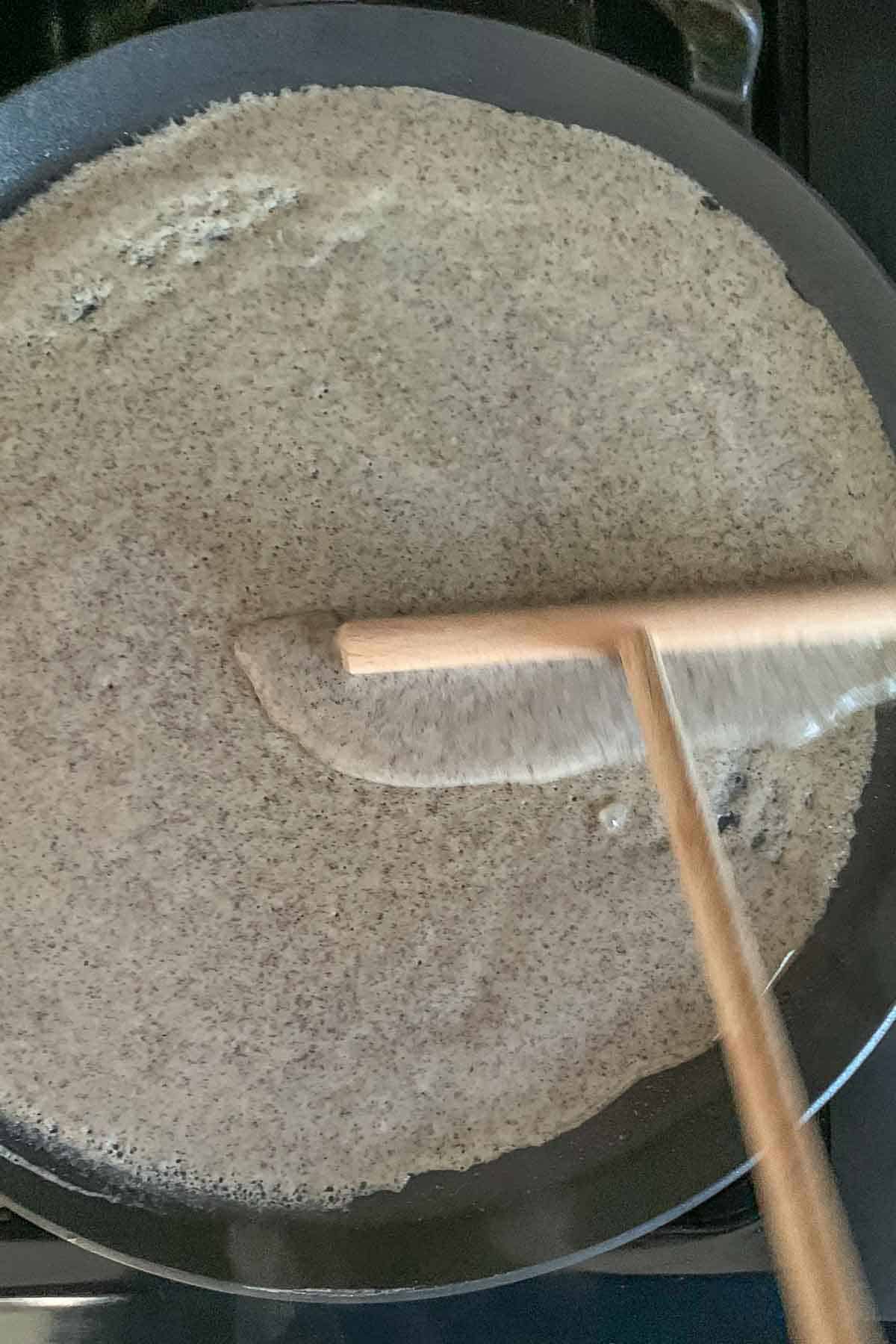 Spreading crepe batter onto a pan.