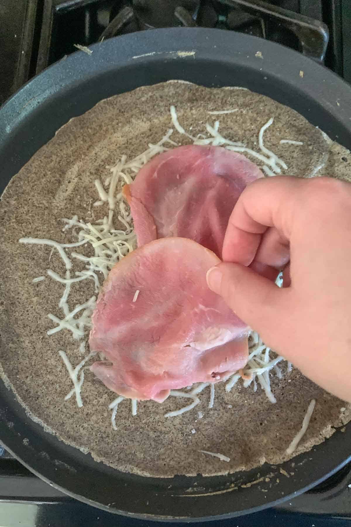 Placing ham onto a buckwheat crepe.