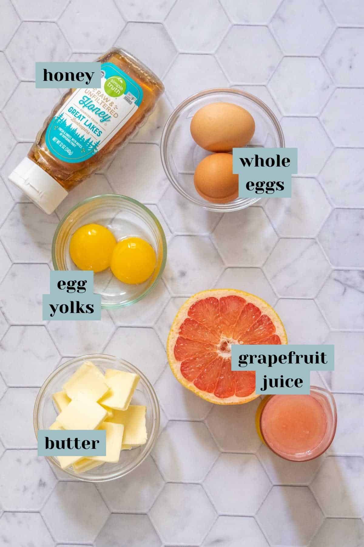 Ingredients for grapefruit curd on a tile surface with labels.