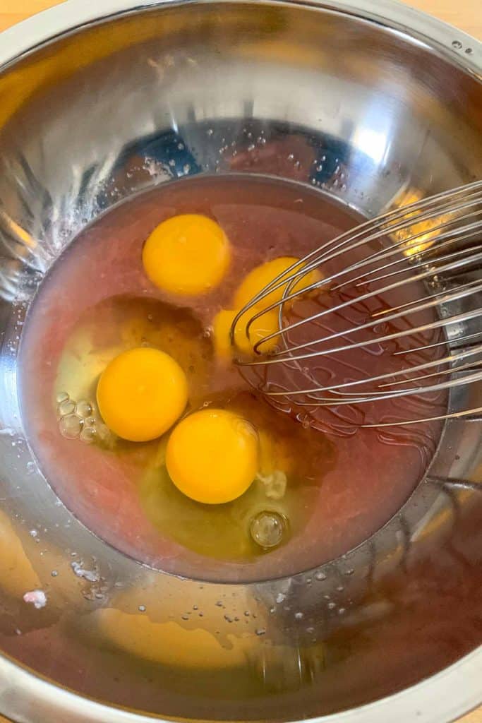 Whisking together ingredients for grapefruit curd in a metal bowl.