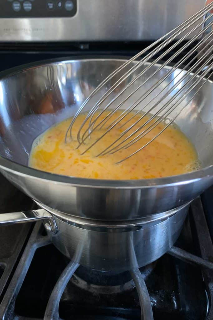 Whisking grapefruit curd over a double boiler.