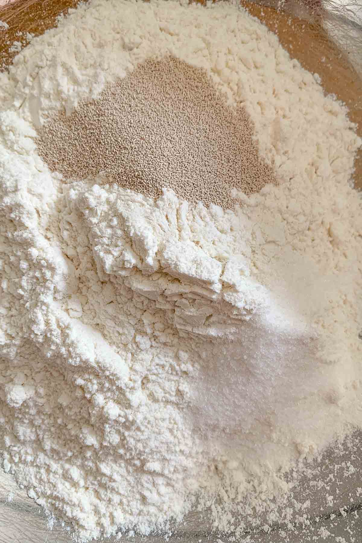 Flour, yeast, and sugar in a mixing bowl.