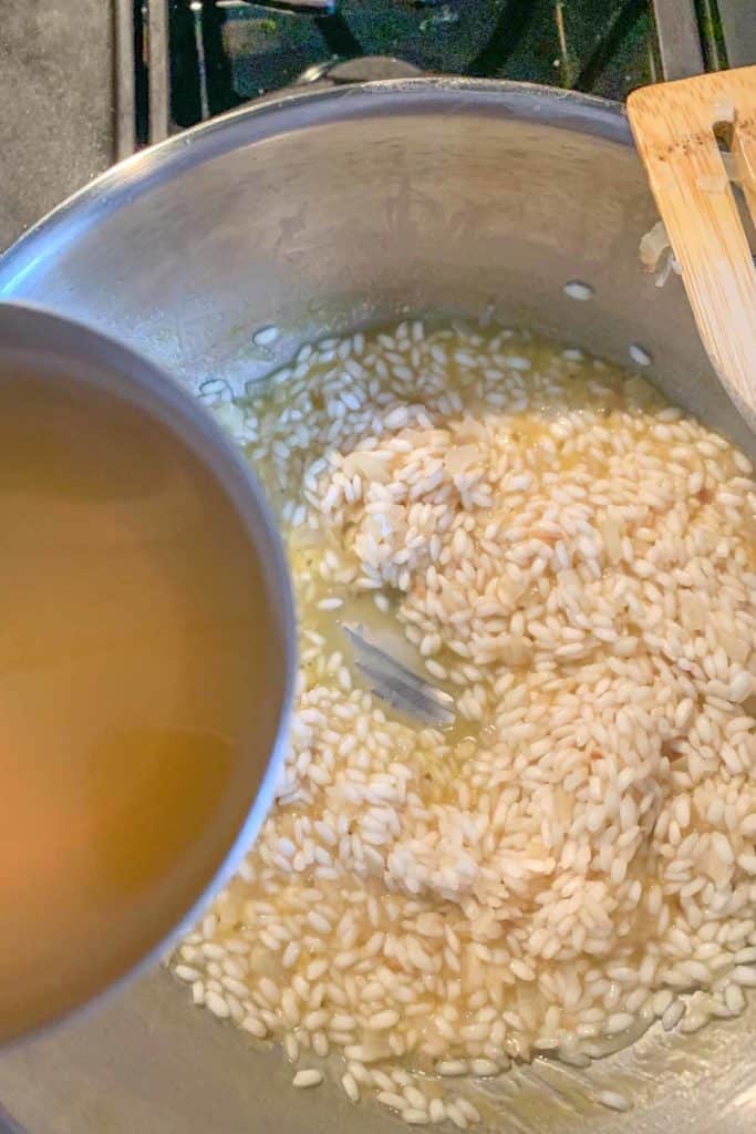 Pouring broth into a pan of risotto.